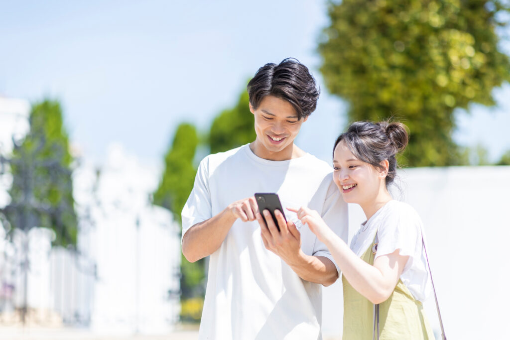 スマホを見る若いカップルの写真